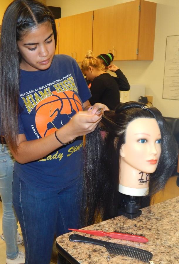 Sophomore cosmetology student Virginia Marrero braiding a dolls hair.