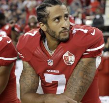 Colin Kaepernick sitting during the natinal anthem. (Source: NBC Sports)