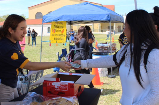 Senior class treasurer Karina Garcia (left) collecting money from a Miami High student (right) at the SGA Carnival 