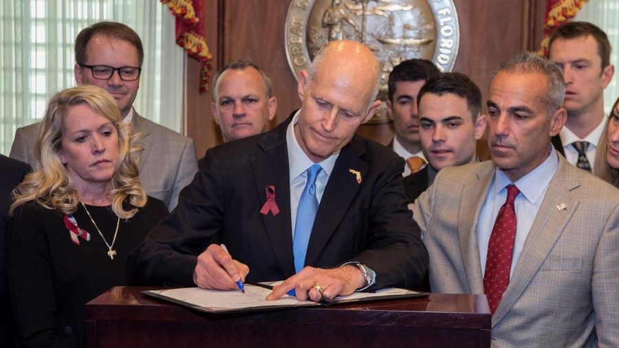 Florida governor Rick Scott (R) signs the “Majority Stoneman Douglas High School Public Safety Act” into law, accompanied by parents of victims of the MSD shooting and by legislative leaders. (nbcnews.com)