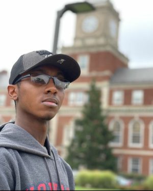 Currently in his junior year, Howard University student Jeremy Gay, standing in front of Founders Library on campus, decked out his university hoodie and bison hat! Photograph taken by fellow Howard University student, Evan Johnson. 