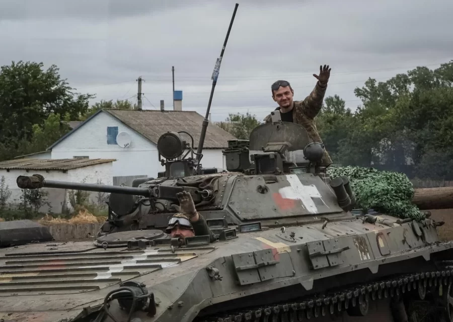 Two  Ukrainian service  members,  pictured waving to the camera  in a  IFV. They  are  two of the marry  troops fighting for  Ukraine freedom.