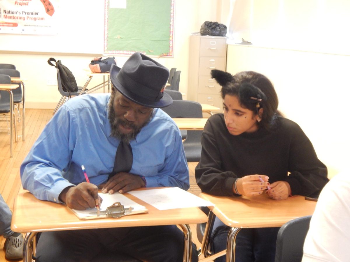 Mr. Strickland assisting a student with their assignment in his classroom.